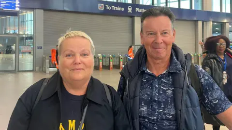 Gerard and Marian looking at the camera, Marian has light hair and Gerard has dark hair.