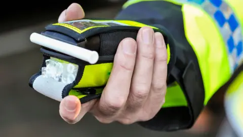 A police officer holding a breathalyser.
