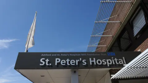 A sign above the entrance to one of the hospitals that reads St. Peter's Hospital. There is a blue sky beyond it.