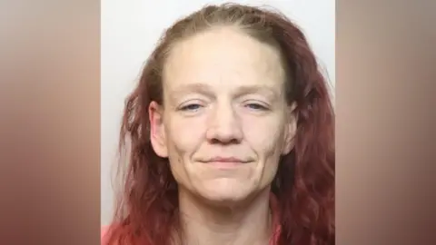 Mugshot of Lisa Kelly, a 40-year-old white woman with dyed-red wavy hair. 