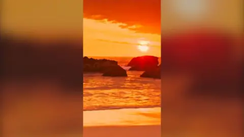 Deep orange sunset over the sea with large rocks in the water