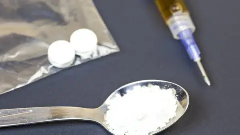 Getty Images Teaspoon holding white powder, a syringe and white tablets