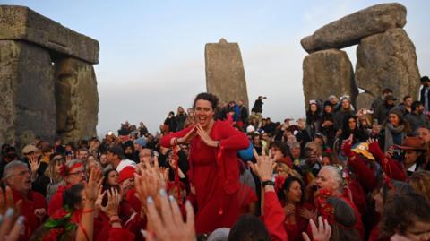Woman in red above crowd dressed in red near  Stonehenge 