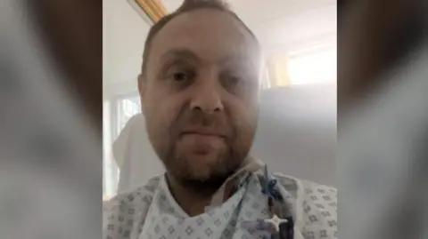 Derbyshire Police PC Daniel Bird pictured in his hospital gown after a transplant operation