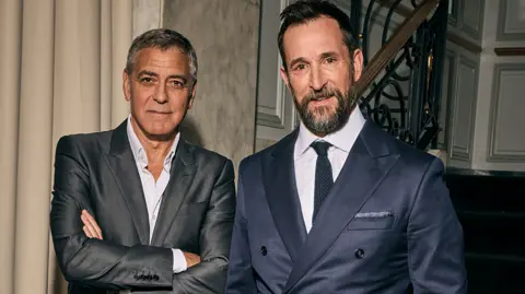 Getty Images George Clooney and Noah Wyle - both in suits looking at the camera.