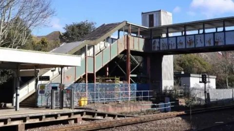 LDRS A look across the platform at Pokesdown station at an aging set of stairs and a bridge over the tracks.