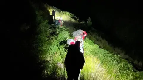 Glossop Mountain Rescue Team Rescue volunteers making their way up a hillside in the dark