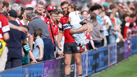 Chris Harris of Gloucester speaks to fans after the final match of the season at Kingsholm. He is carrying his young daughter