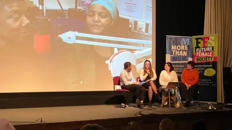 Jon Wright/BBC Four women sit on a stage, speaking into a microphone. There is a video screen behind them with an image of two women in a radio studio