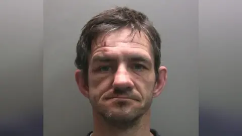 Cumbria Police A mug shot of an unshaven man with facial injuries 