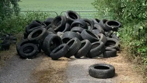 Frogmore Farm A pile of tyres next to a farm gate.