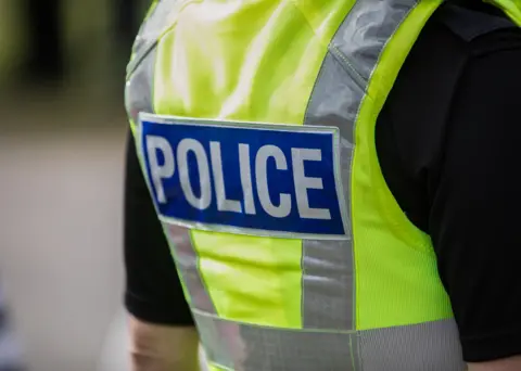 Getty A police officer shown from the back, wearing a high-vis yellow vest.