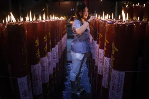 Timur Matahari/AFP A woman lights a prayer candle at Darma Ramsi Temple in Bandung, West Java, Indonesia