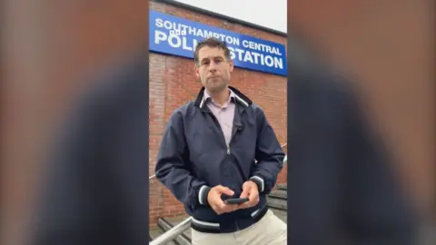 Nick Johnson stands outside a Southampton Central Police Station sign. He is wearing a navy jacket and looks at the camera.