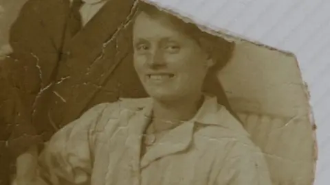 PA Media Louisa Dunne pictured smiling, wearing a light coloured dress. The picture is sepia and has been ripped in the corner.
