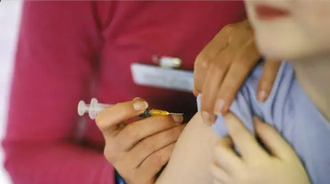 A close-up image of a person about to have a needle placed into their arm.