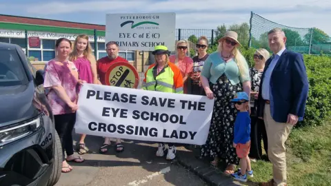 Protesters standing in front of the Eye School holding a banner