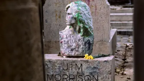 The bust of Jim Morrison, covered with graffiti, at his grave in Paris's famous Père-Lachaise cemetery