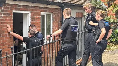 Five police officers stand outside a business in Ipswich while looking inside.