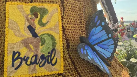 A yellow knitted square with a dancer and the word 'Brazil' at the bottom. To the right is a large blue and black butterfly.