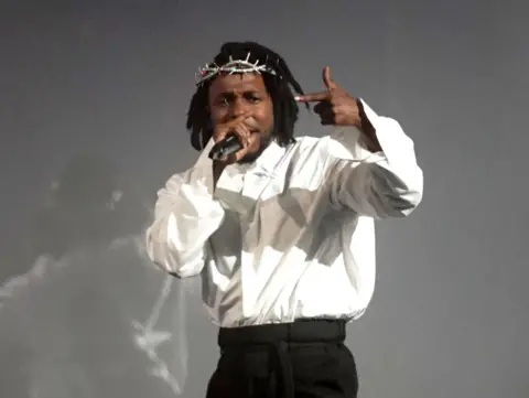 PA Media Kendrick Lamar, wearing a silver crown of thorns, performs at the Glastonbury Festival