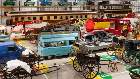 Science Museum Group Looking down on a colourful collection of vintage vehicles, including horse cars, submarines, fire engines, cars and vans.