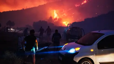 Getty Images Flames can be seen through smoke on a hillside in the Seferihisar district of Izmir