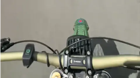 Thames Valley Police Close-up of a green customised electric motorbike showing the handlebars and an RAF-style marking on the front mudguard.