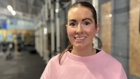 Woman in pink jumper smiles at camera