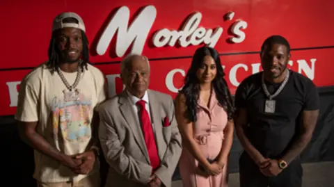 London Museum Musicians Krept and Konan (far left and right) stand with Sydenham Morley’s manager Kannalingam Mahendran and his daughter Janani Nageswaran, with the original Morley’s sign visible behind them.