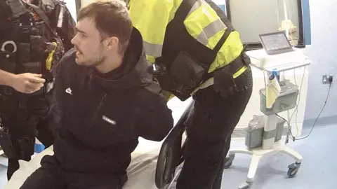 Nottinghamshire Police Adam Watson being arrested by police officers with hospital equipment in the background