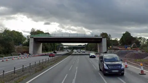 A bridge that runs over a motorway, but is not connected to at either side, meaning it is inaccessible to vehicles. 