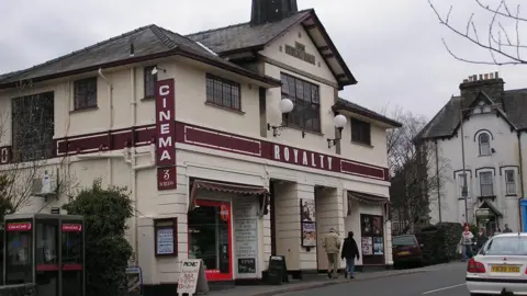 Wide shot of Royalty cinema building with people walking by in front.