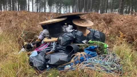 Forestry England A pile of rubbish in the forest, including cables.