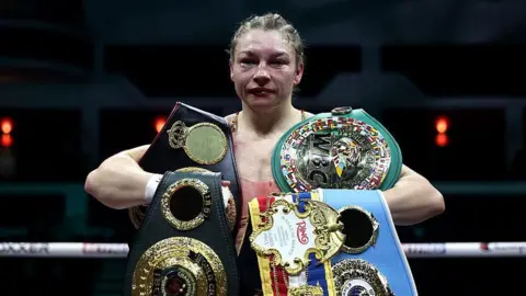 Getty Images Lauren Price poses for a photo with her belts following victory in the Women's WBA, WBC, IBF, IBO and Ring Magazine World Welterweight Titles' fight 