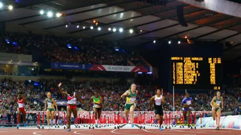 Getty Images oito corredores de barreira competindo nos jogos da Commonwealth de 2014 no estádio Hampden