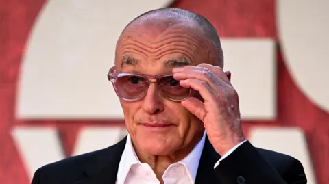 Danny Boyle adjusts his glasses as he poses for photographers at the 28 Years Later premiere.