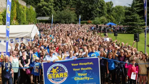 Stars Appeal A large crowd of people all facing the camera and waving