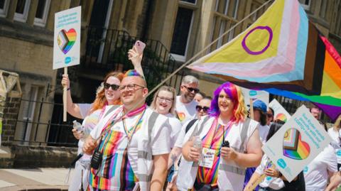 Group wearing rainbows march in sunshine