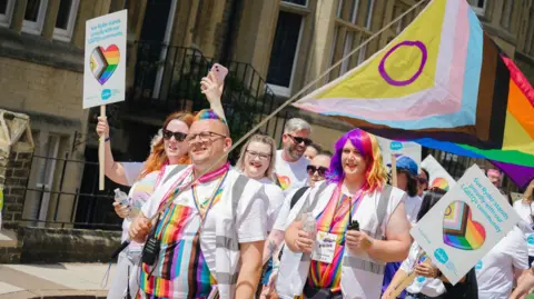 Peterborough Pride Group wearing rainbows march in sunshine