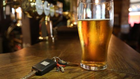 Car keys next to a pint of beer