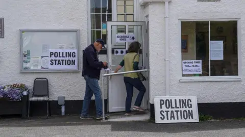 Getty Images A man and a woman entering a polling station in Hastings