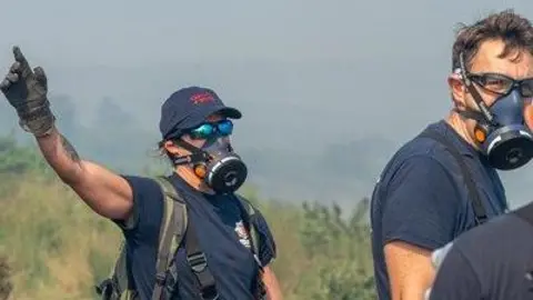 A firefighter with a mask stands in the middle of moorlands