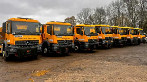 Oxfordshire County Council A row of the newly named yellow gritters, with names such as Spready Mercury, Radiospread and Claudia Sprinkleman.