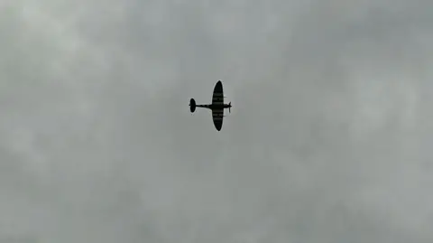 A Spitfire outlined against a cloudy sky