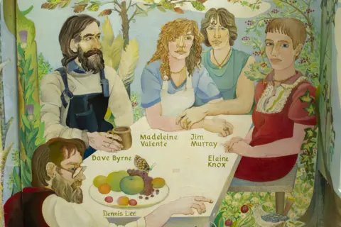 Alasdair Gray Detail of Arcadia mural at the Ubiquitous Chip - the painting depicts a group seated around a table in a garden. The scene includes foliage such as thistles and fruit trees. The people are labelled as Dave Byrne, Denis Lee, Madeleine Valente, Jim Murray and Elaine Knox.