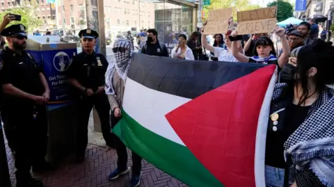 Reuters Protesters hold up a Palestinian flag and stand next to police outside of the Columbia University campus