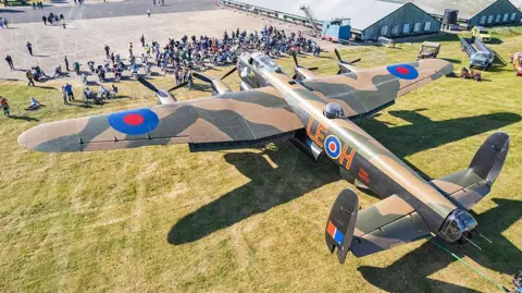 A large Lancaster bomber plane in front of crowds at an air show