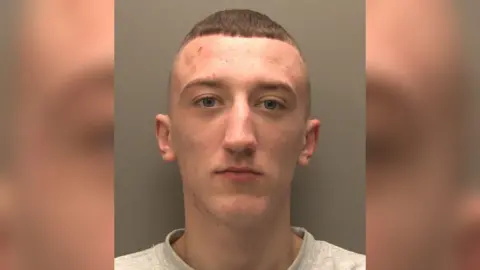 Lincolnshire Police A police-issued custody image of a man with cropped brown hair wearing a grey sweatshirt