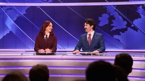 Sky UK Ania Magliano and Paddy Young as news anchors at a set with a map of the world seen behind them 